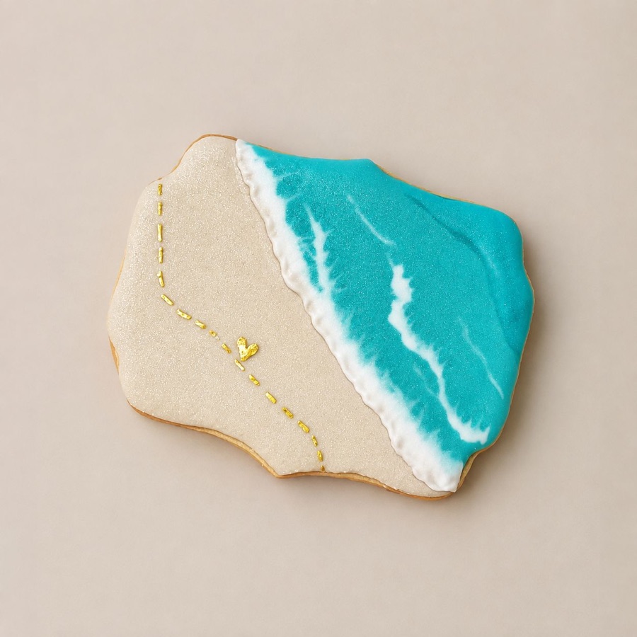 A cookie iced as a beach scene, turquoise sea meeting pale sand